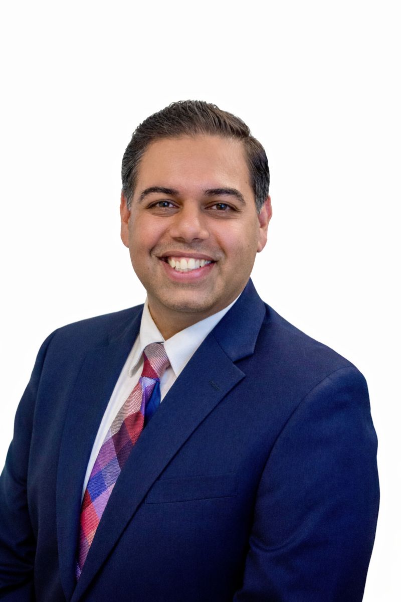Dr. Rushikesh Vyas, psychiatrist, smiling in a professional suit with a colorful tie, emphasizing patient-centered mental health care.
