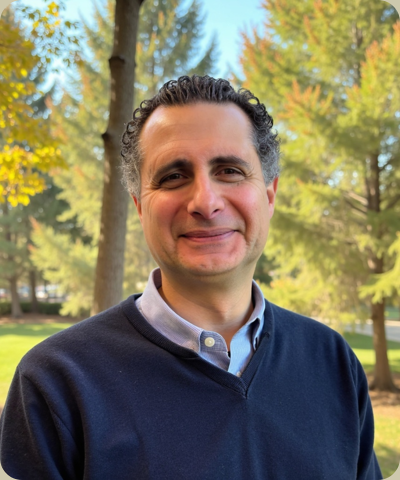 Smiling male psychiatrist outdoors, surrounded by trees, representing MedPsych Health's compassionate mental health care services for families in Northern New Jersey.